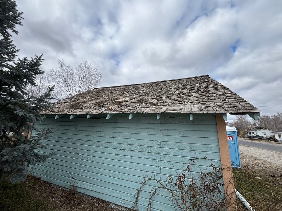 Building before new roof — worn and damaged old shingles