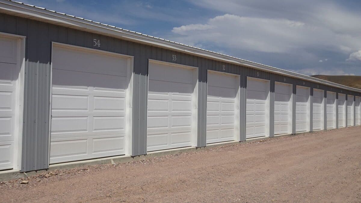 Row of storage units with white garage doors at Sugar Factory Storage Complex