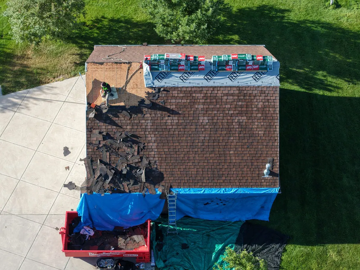 Crew tearing off shingles with GAF materials staged on the roof